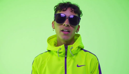 Gen-Z model in mismatched neon green & purple Nike Tech tracksuit, oversized sunglasses. Funny streetwear fashion.